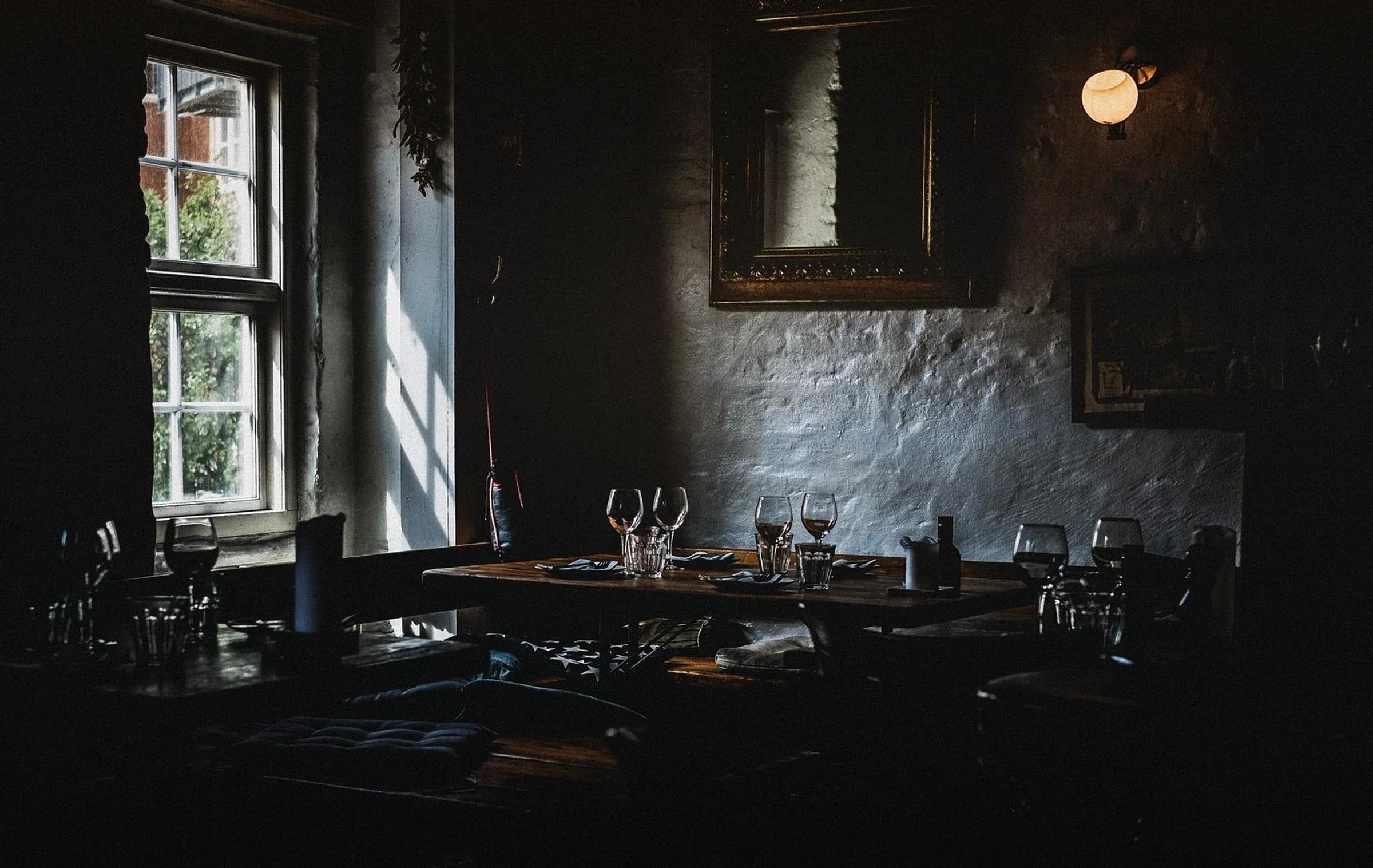 La sala vecchia: pietra, legno scuro, i calici sui tavoli