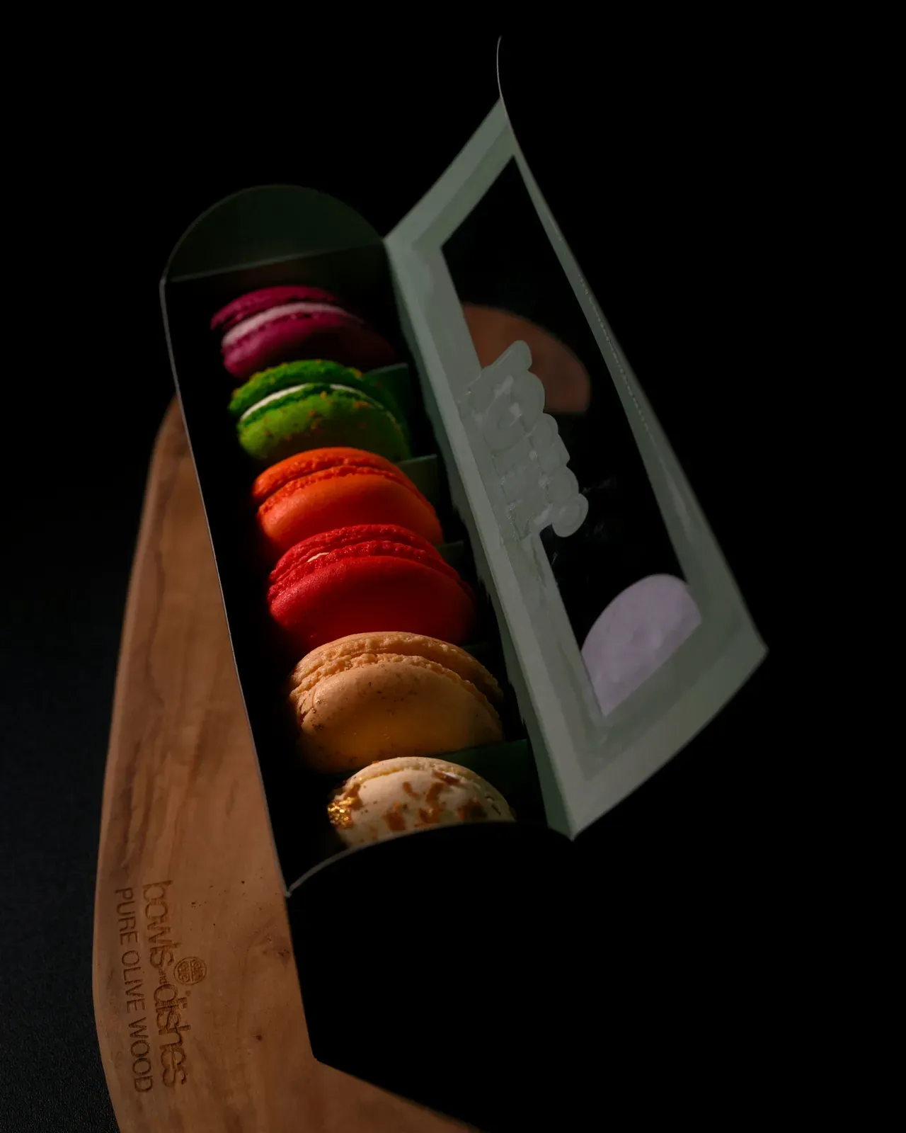 La box di macarons aperta, su fondo scuro