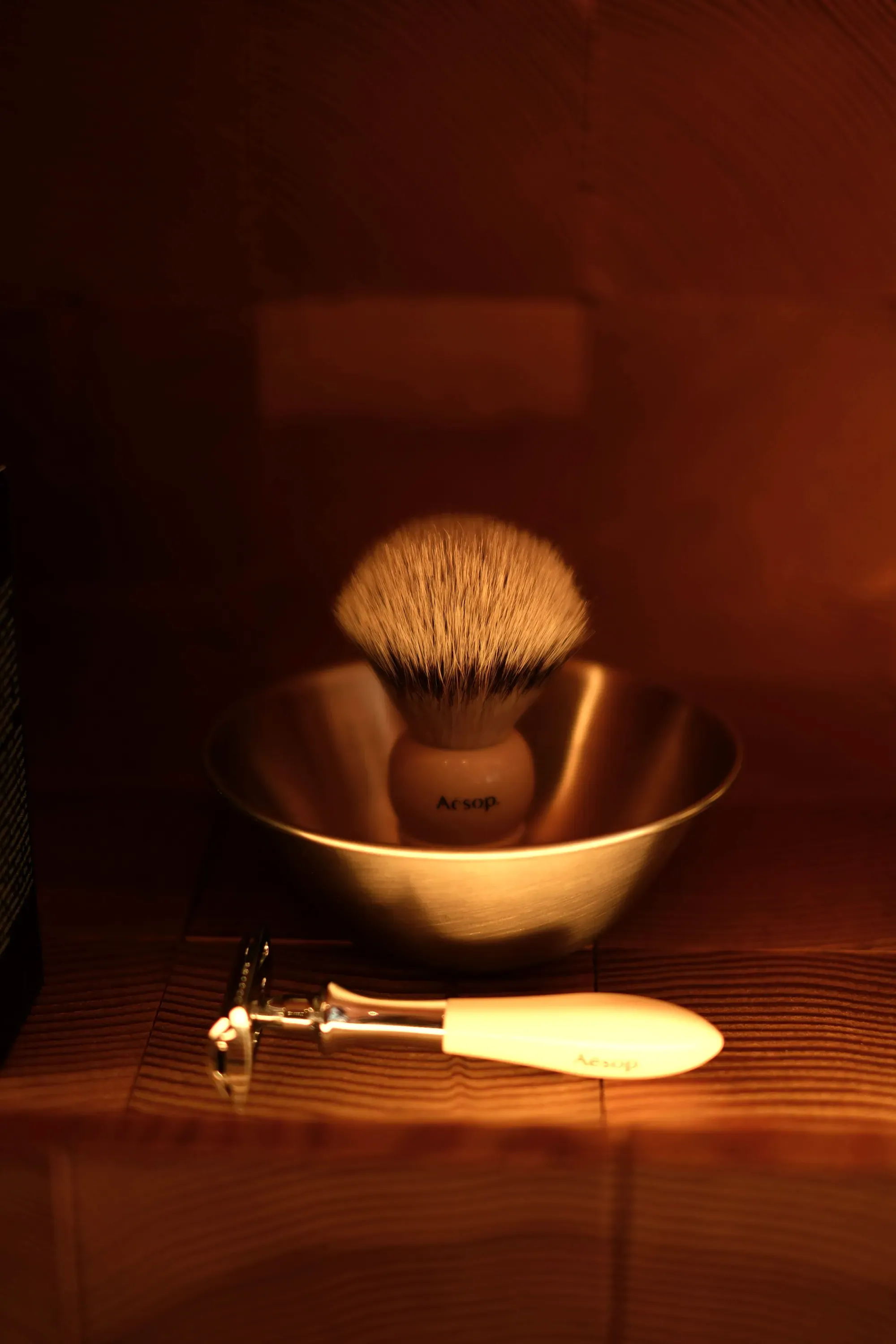 La ciotola in ottone con il pennello da barba, nella luce calda