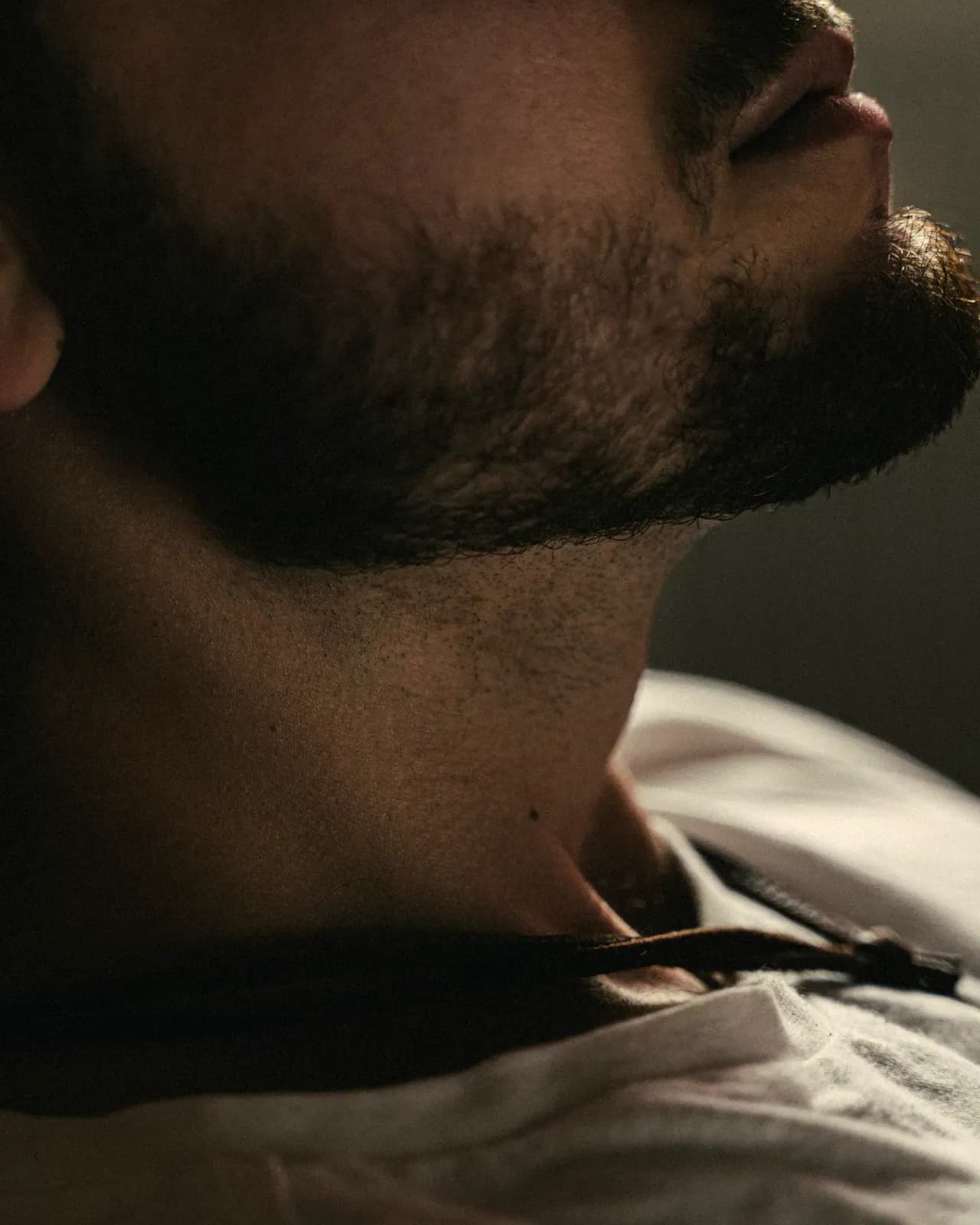 Il rasoio sul collo, la barba definita, nella penombra