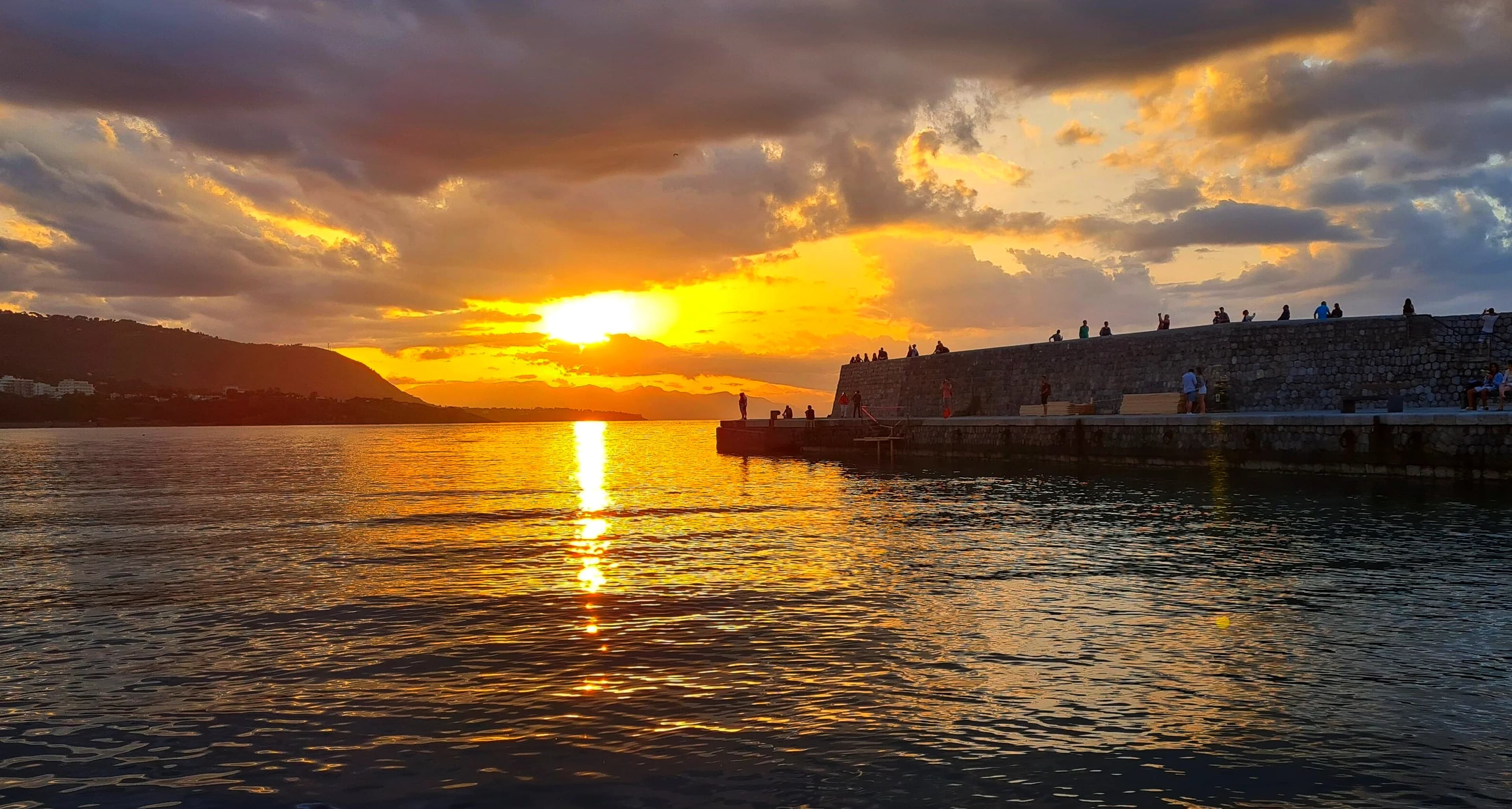 Il tramonto sul mare davanti alla terrazza di Marevia, le luci del paese che si accendono