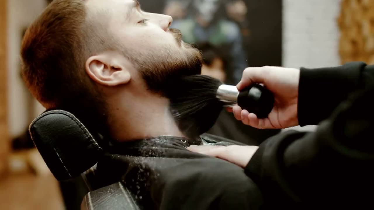 Il cliente in poltrona con la testa indietro, il pennello sulla barba