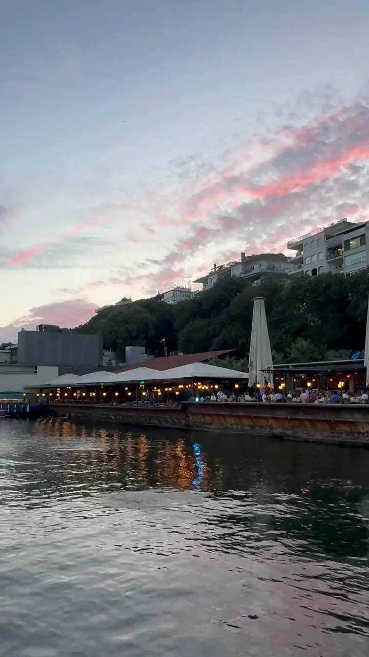 La terrazza del ristorante sul mare al crepuscolo, le luci accese, le nuvole rosa