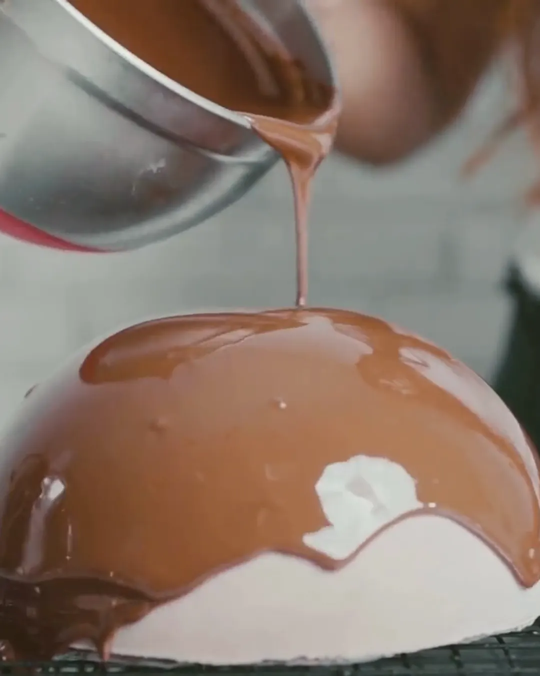 La glassa al cioccolato che cola sulla cupola di mousse, in laboratorio